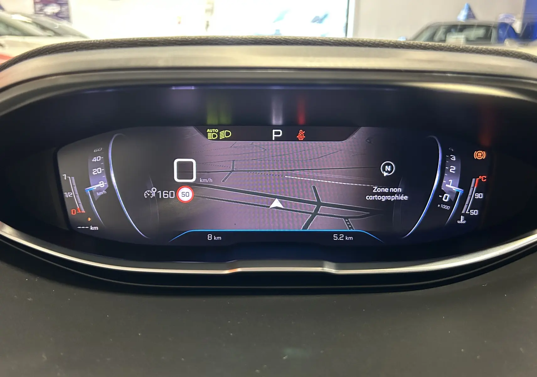 Tableau de bord numérique du Peugeot 5008 2024 affichant la navigation et les voyants, vue frontale intérieure.