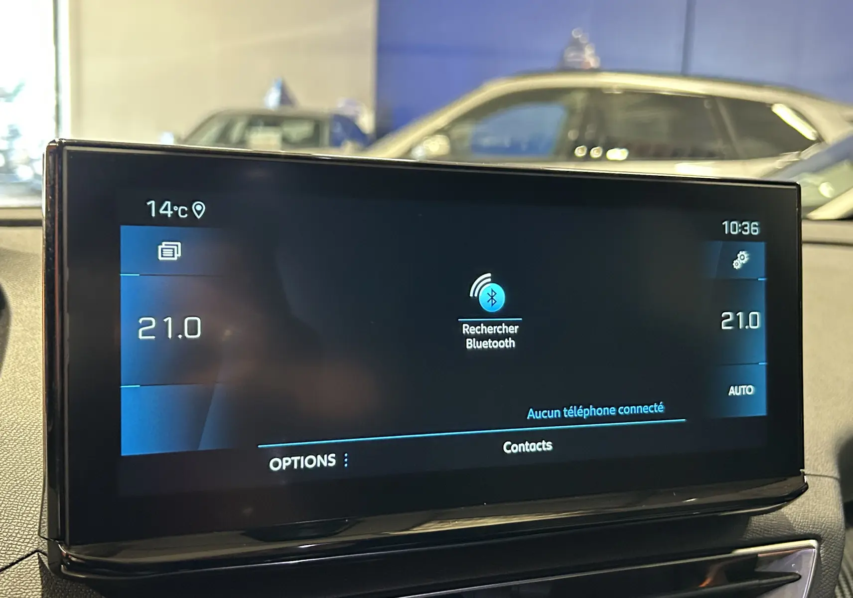 Écran tactile central du Peugeot 5008 2024 affichant la recherche Bluetooth, avec tableau de bord et vitre arrière flous en arrière-plan.