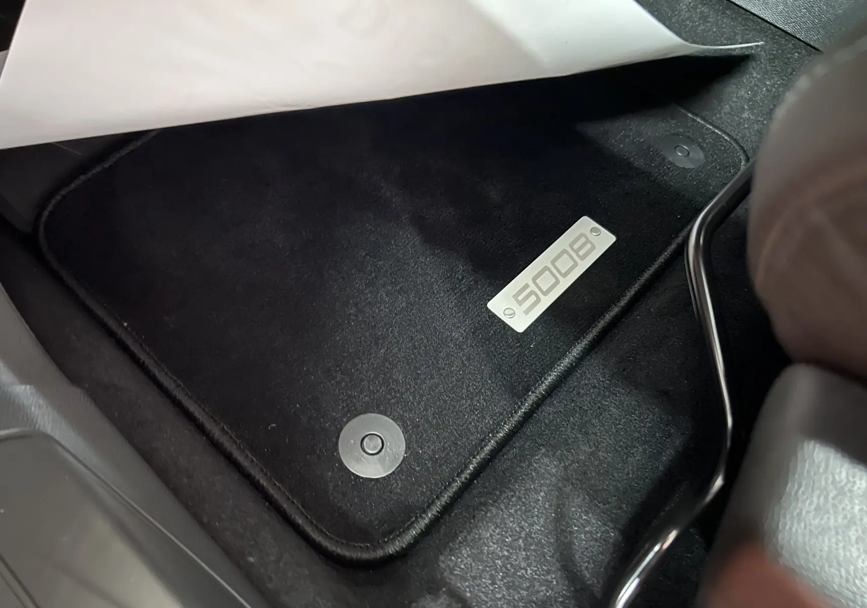 Gros plan sur le tapis de sol noir avec logo 5008 à l'avant droit du Peugeot 5008 Gris Platinium 2024.