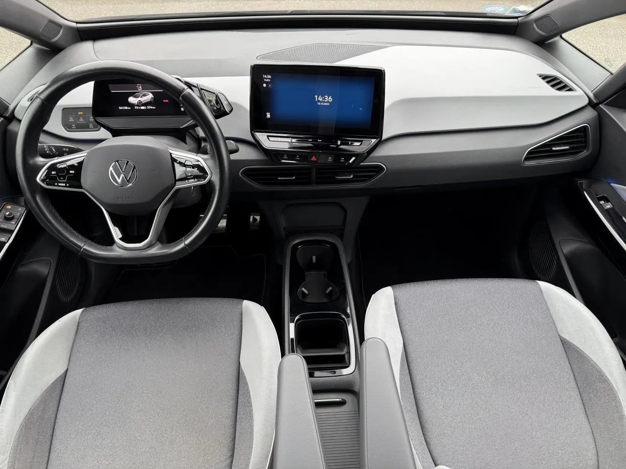 Intérieur avant du Volkswagen ID.3 2022 avec tableau de bord clair, volant cuir noir et écran tactile central.