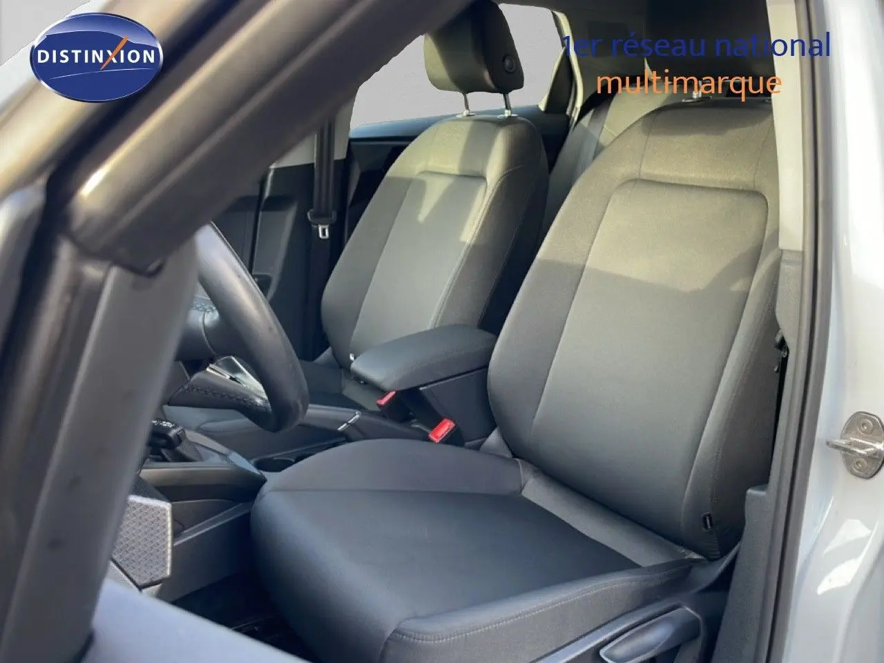 Vue intérieure côté conducteur de l'Audi A1 Sportback 2023 blanc glacier, sièges tissu gris et volant visible.