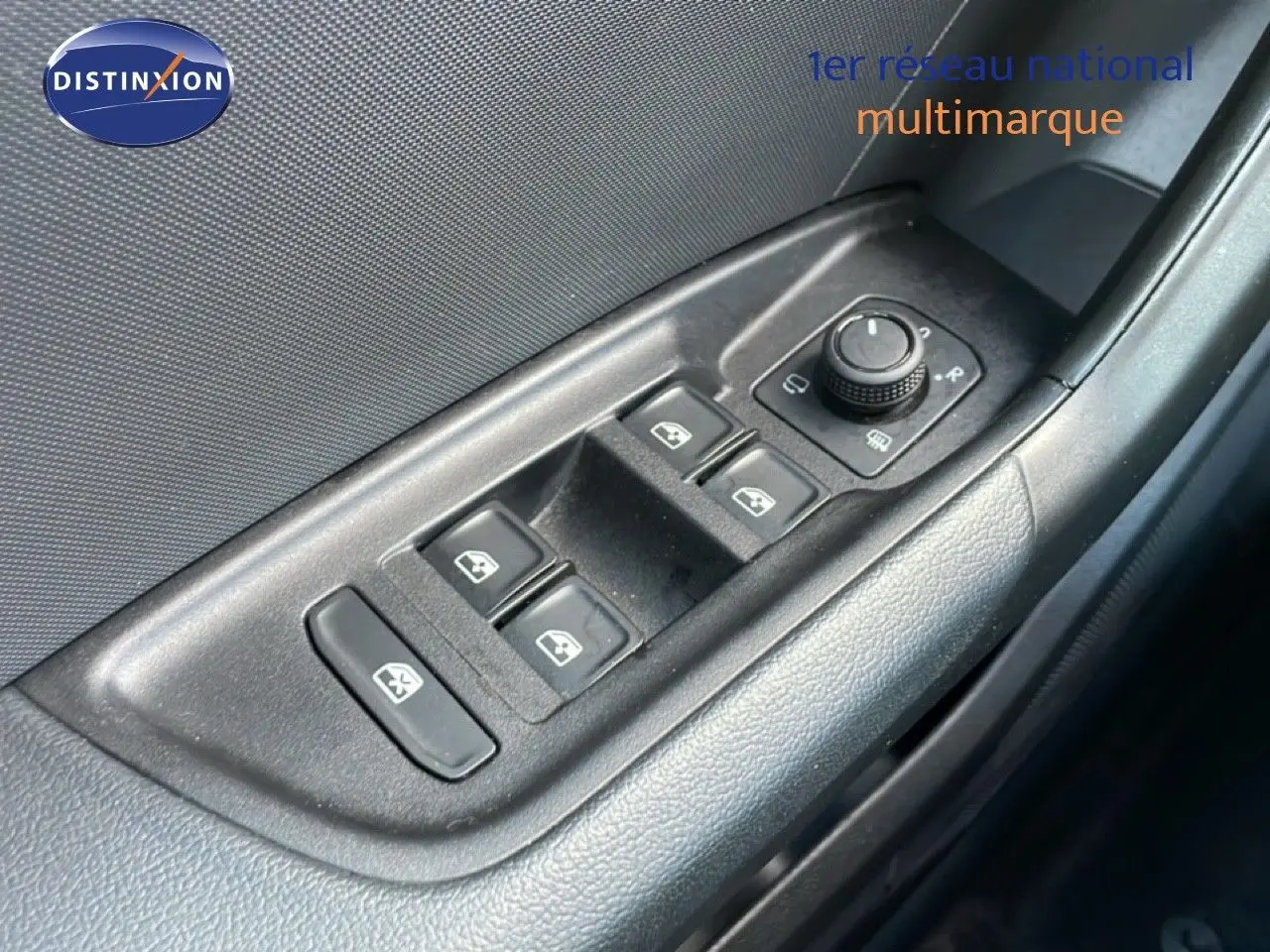 Gros plan sur les commandes des vitres électriques et rétroviseurs d'une Audi A1 Sportback blanche, côté conducteur.