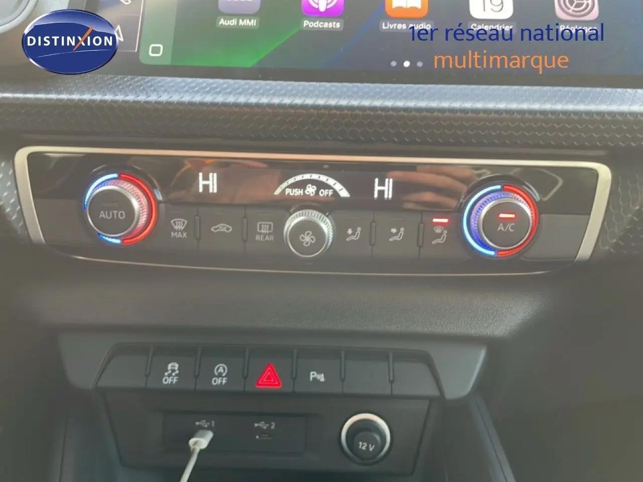 Tableau de bord de l'Audi A1 Sportback 2023 montrant la climatisation automatique avec réglages en rouge et bleu.