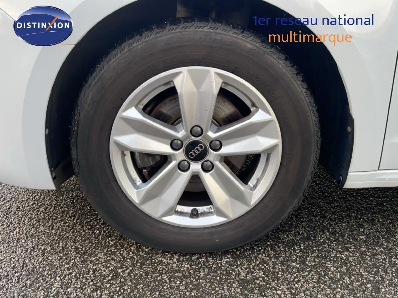 Gros plan sur la roue avant gauche d'une Audi A1 Sportback blanche glacier métal avec jante alliage 15 pouces.