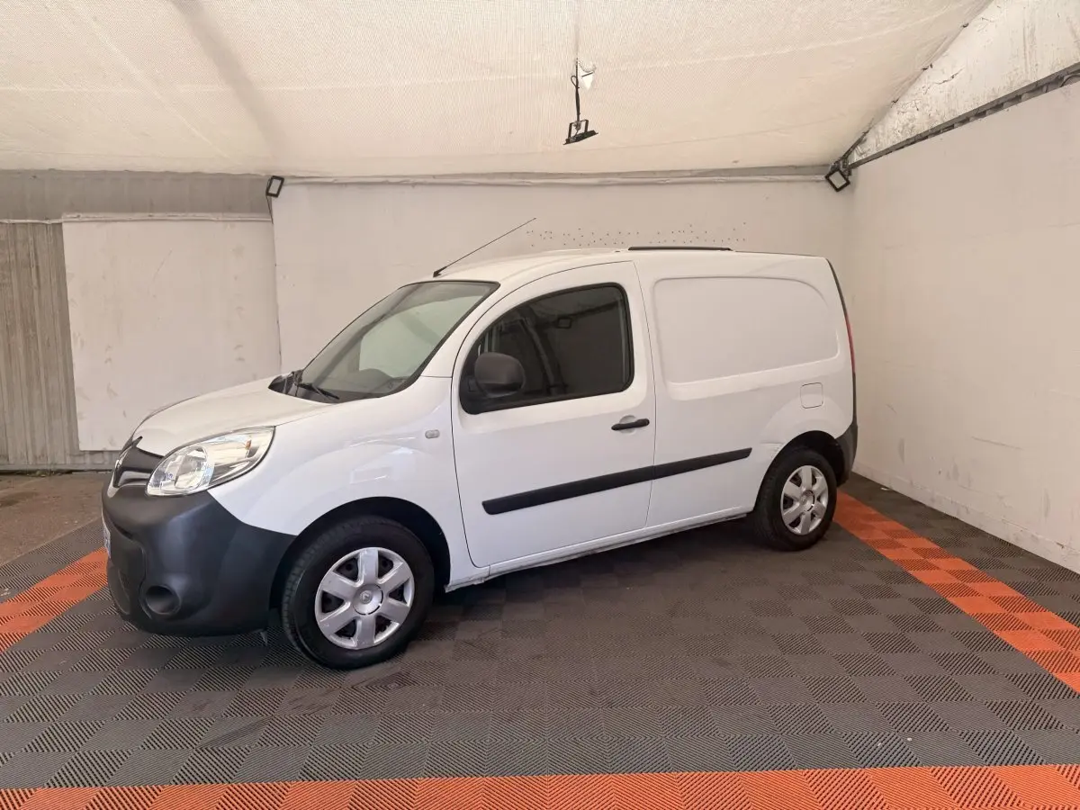 Renault Kangoo blanc en 3/4 avant droit, fourgonnette avec pare-chocs noir et vitres teintées.