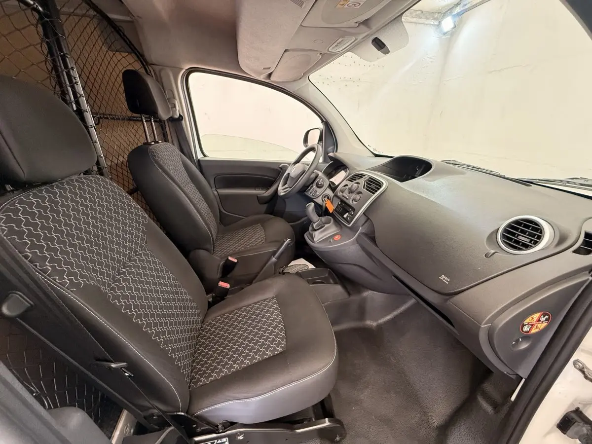 Vue intérieure côté conducteur du Renault Kangoo blanc 2016, montrant les sièges avant et la cloison tubulaire.