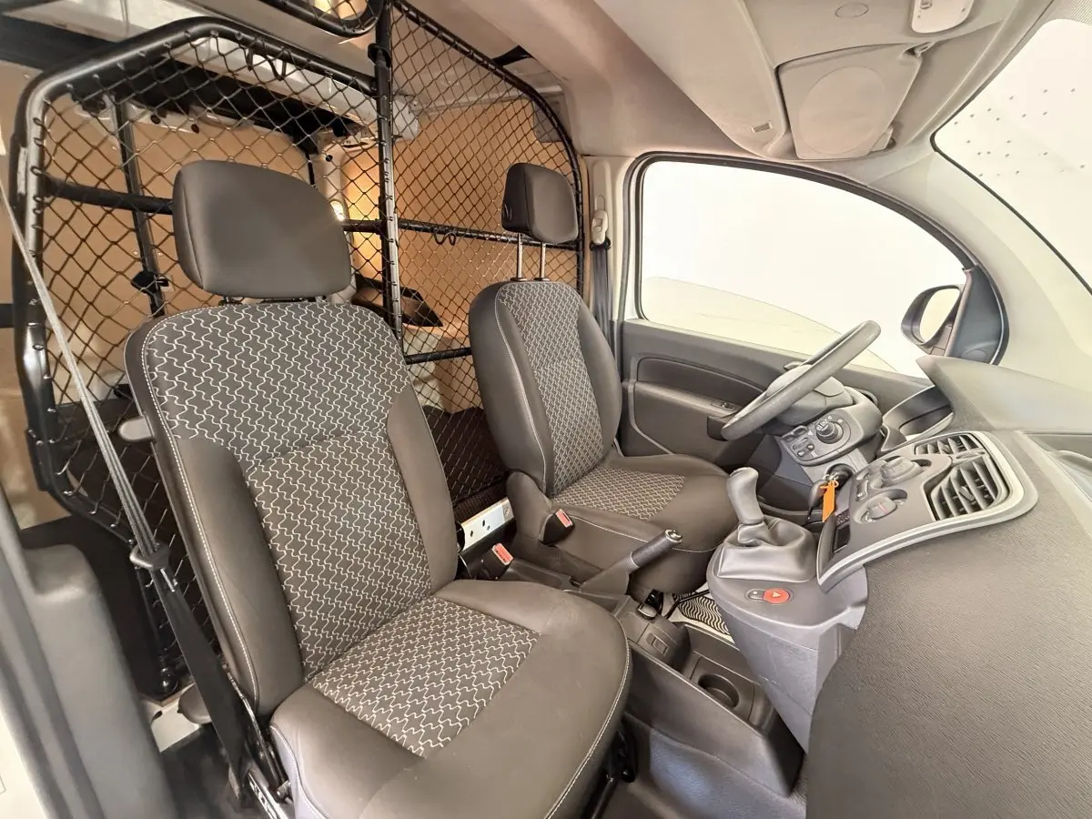 Vue intérieure côté conducteur du Renault Kangoo blanc 2016 avec cloison tubulaire et sièges gris à motifs.
