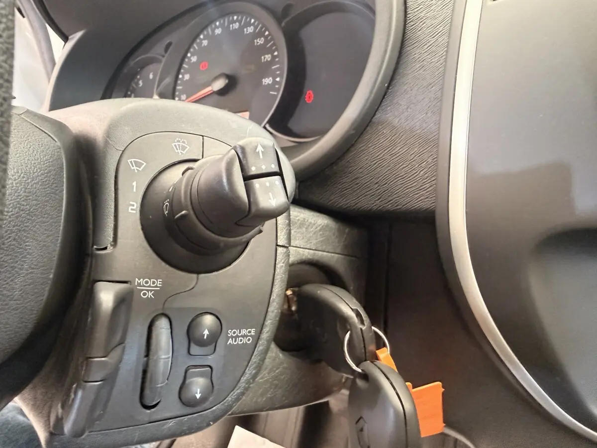 Gros plan sur le volant et le tableau de bord du Renault Kangoo 2016, avec commandes audio et clé insérée.