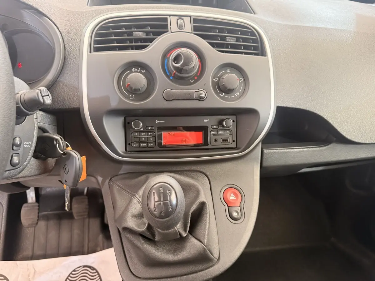 Vue intérieure centrée sur la console centrale et levier de vitesses manuelle du Renault Kangoo blanc de 2016.