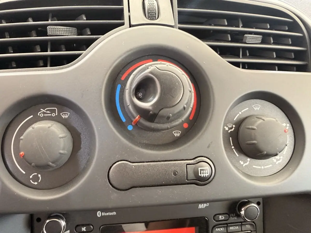 Gros plan sur les commandes de climatisation et radio Bluetooth du tableau de bord du Renault Kangoo blanc de 2016.