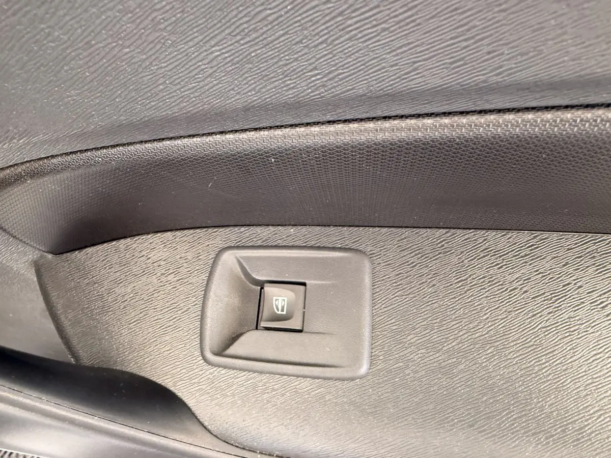 Gros plan sur le bouton de commande de la vitre électrique côté conducteur du Renault Kangoo blanc, intérieur noir.