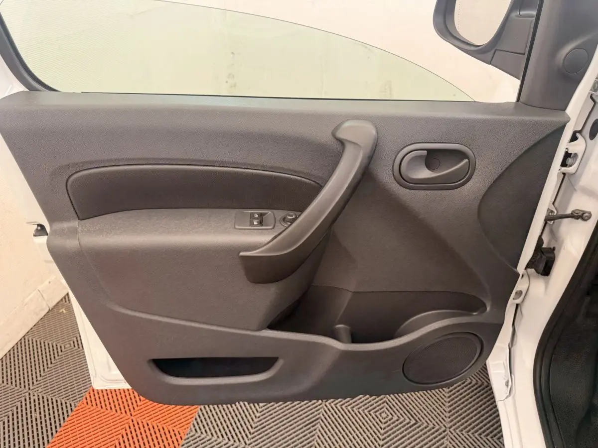 Vue intérieure de la porte avant gauche du Renault Kangoo blanc, avec poignée et commandes de vitres électriques.