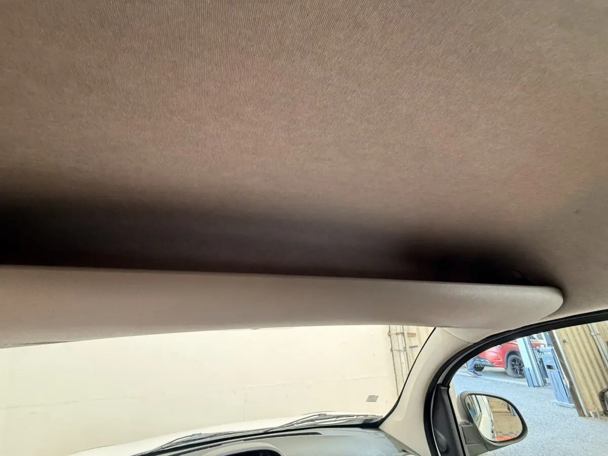 Vue intérieure côté passager du Renault Kangoo blanc 2016, montrant le pare-soleil et le rétroviseur extérieur.