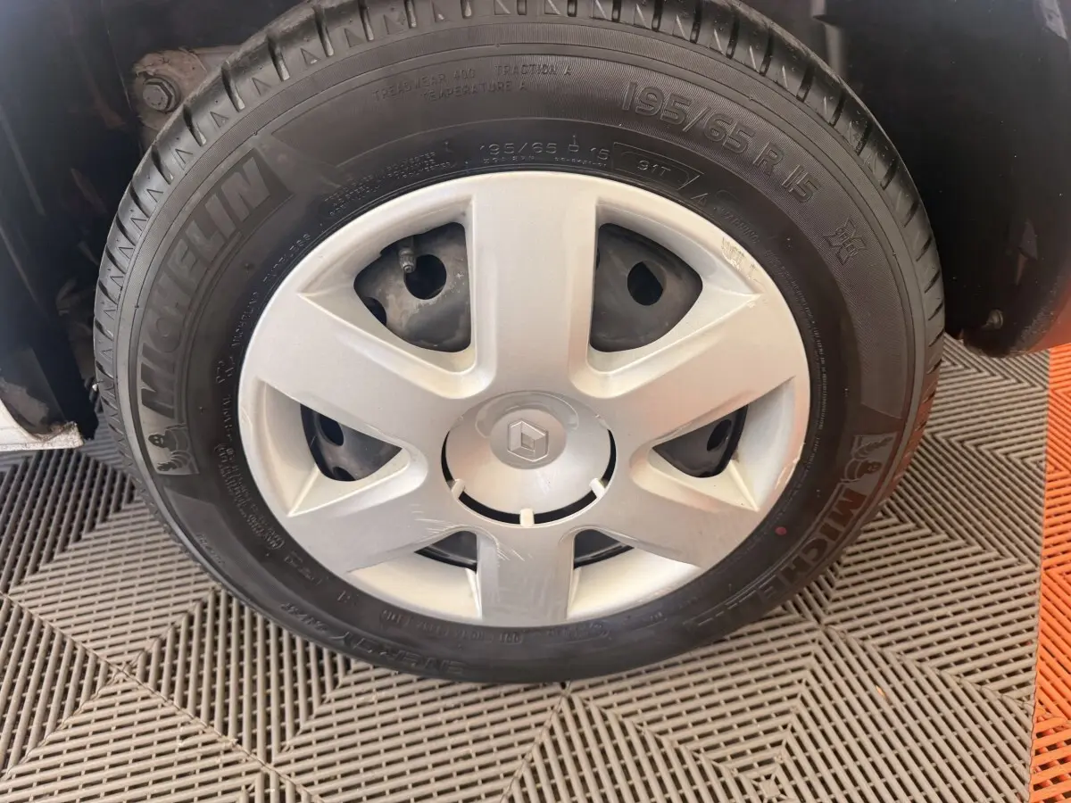 Gros plan sur la roue avant droite d’un Renault Kangoo blanc avec jante acier et pneu Michelin.