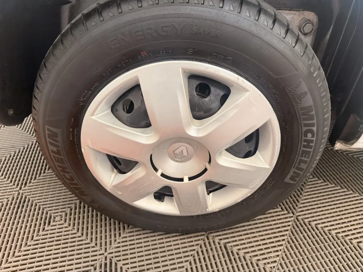 Gros plan sur la roue avant droite d'un Renault Kangoo blanc avec jante acier et logo Renault au centre.