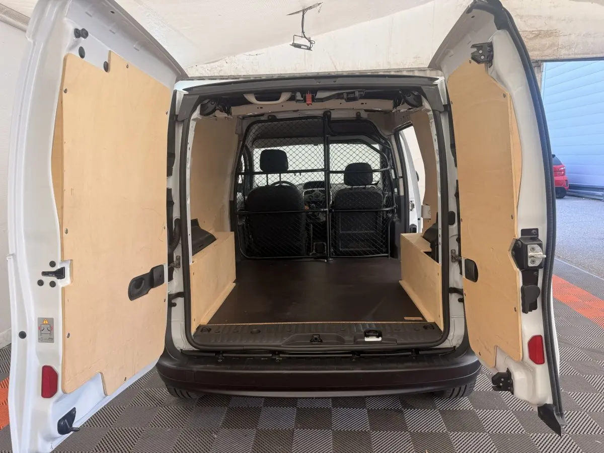 Vue arrière du Renault Kangoo blanc 2016 avec portes ouvertes montrant l'espace de chargement protégé par une cloison tubulaire.