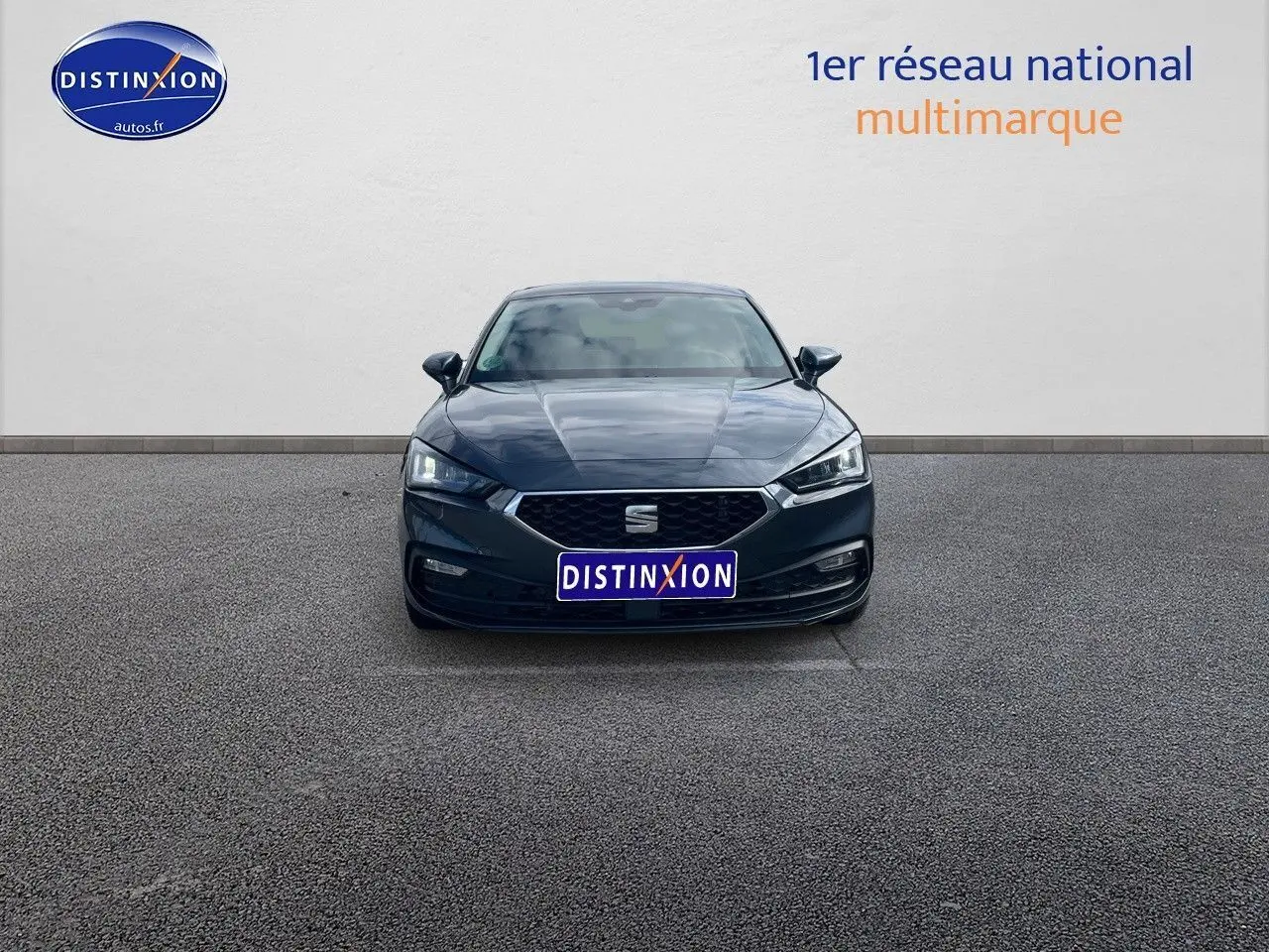 Vue frontale d'une SEAT LEON IV gris magnétique métal, avec calandre hexagonale et phares LED allumés.