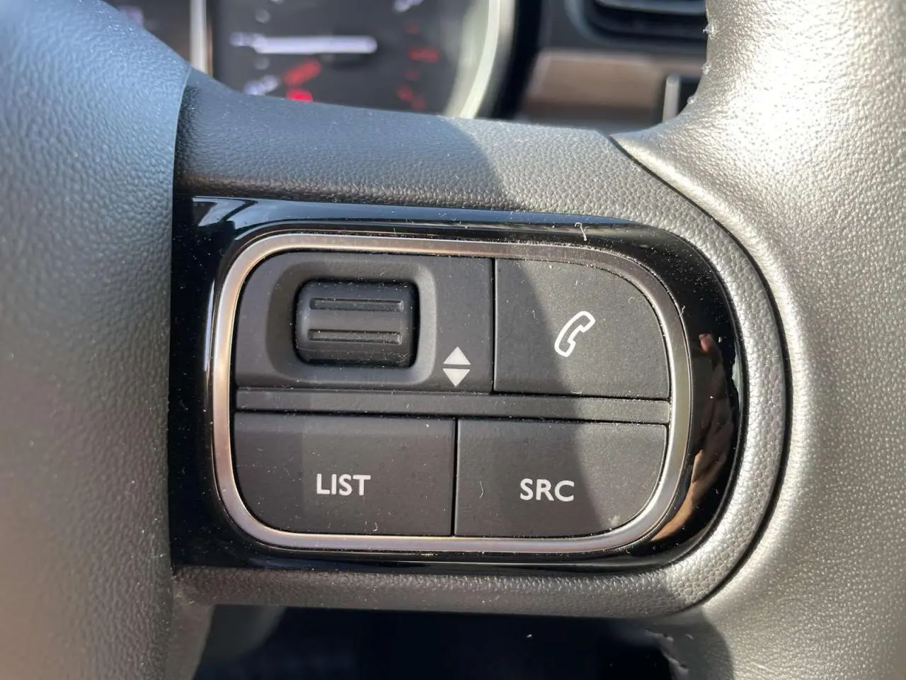 Gros plan sur les commandes audio au volant du Citroën C3 1.2 83 Shine, intérieur noir.