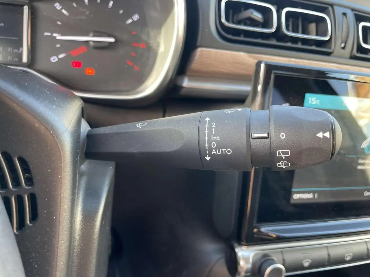 Gros plan sur la commande d’essuie-glace à gauche du volant dans l’habitacle d’une Citroën C3 gris foncé 2021.