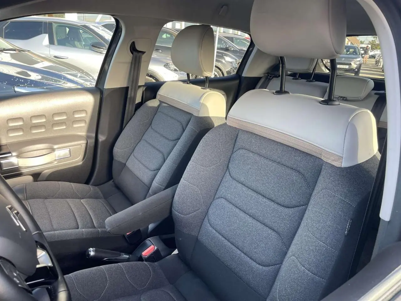 Intérieur de la Citroën C3 2021, vue côté conducteur, sièges bi-ton gris foncé et clair avec accoudoir central.