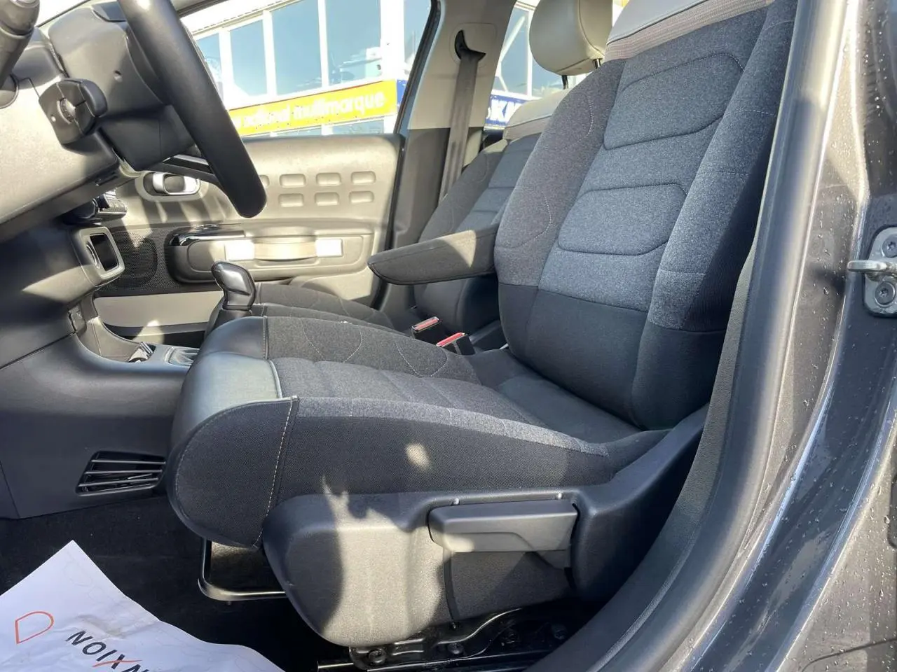 Intérieur côté conducteur de la Citroën C3 1.2 Shine 2021 gris foncé, sièges tissu et cuir avec levier de vitesse manuel visible.