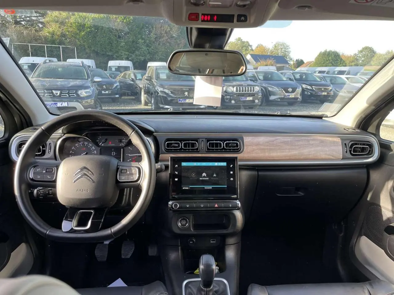 Intérieur de la Citroën C3 1.2 83 Shine 2021, tableau de bord noir avec insert bois et écran tactile central visible.