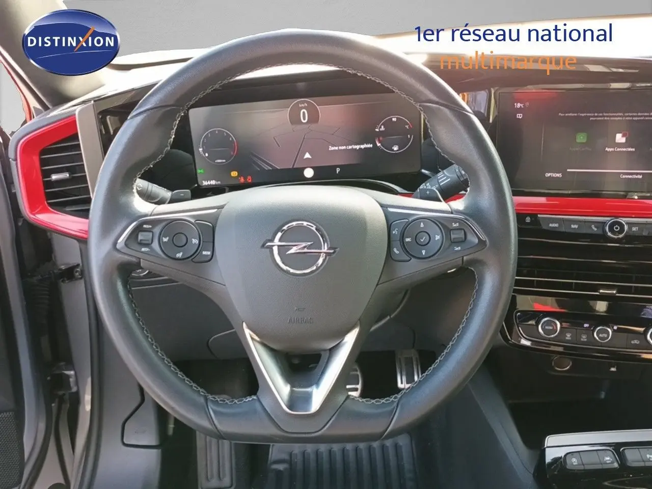 Vue rapprochée du volant Opel Mokka GS Line 2022 avec tableau de bord numérique et inserts rouges autour de la console centrale.