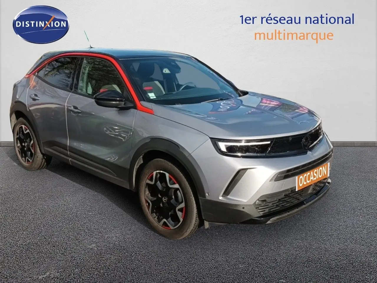 Opel Mokka GS Line gris quartz en 3/4 avant droit avec jantes noires et touches rouges distinctives.