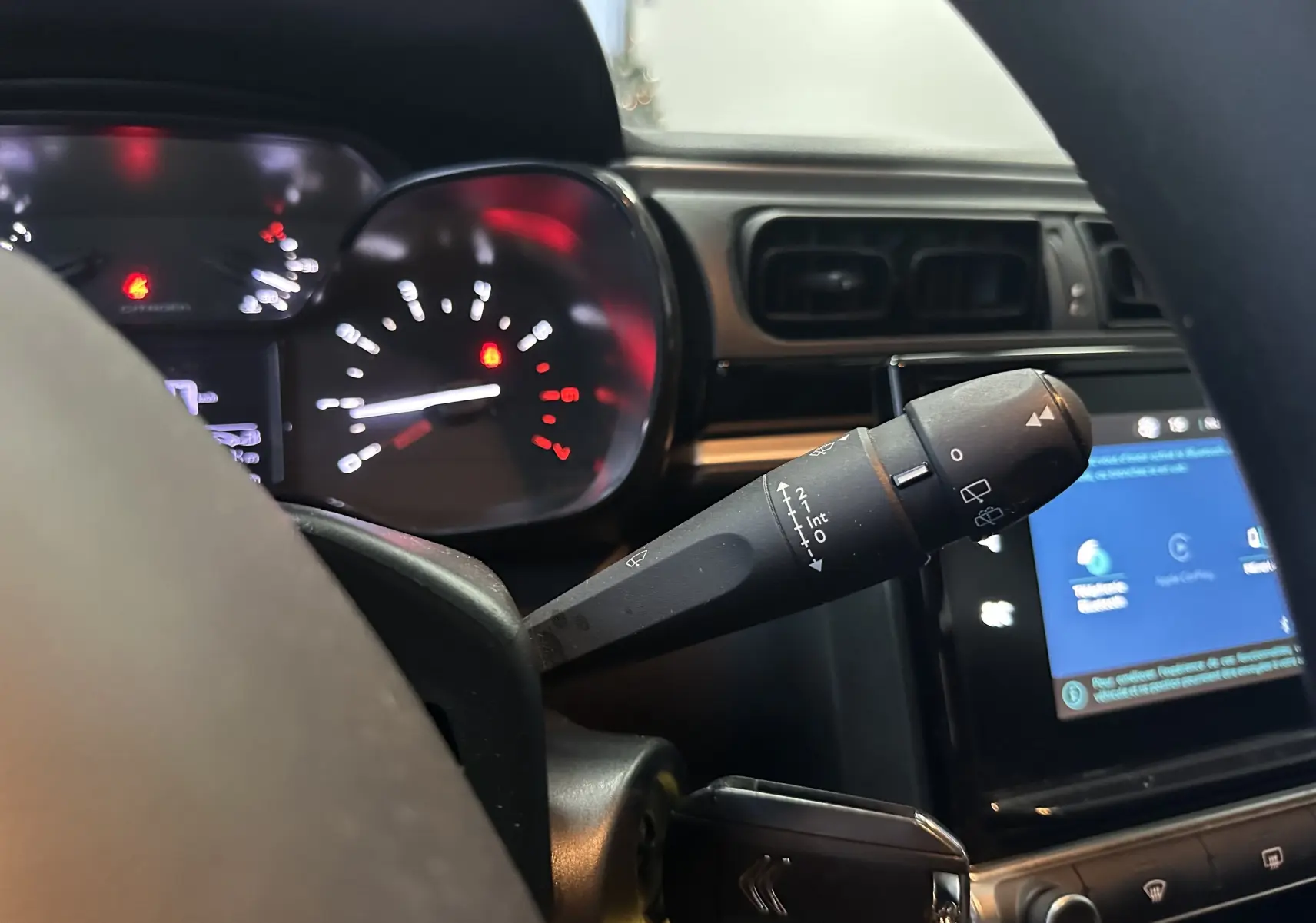 Gros plan sur la commande d’essuie-glace à gauche du volant dans l’habitacle d’une Citroën C3 blanche de 2018.