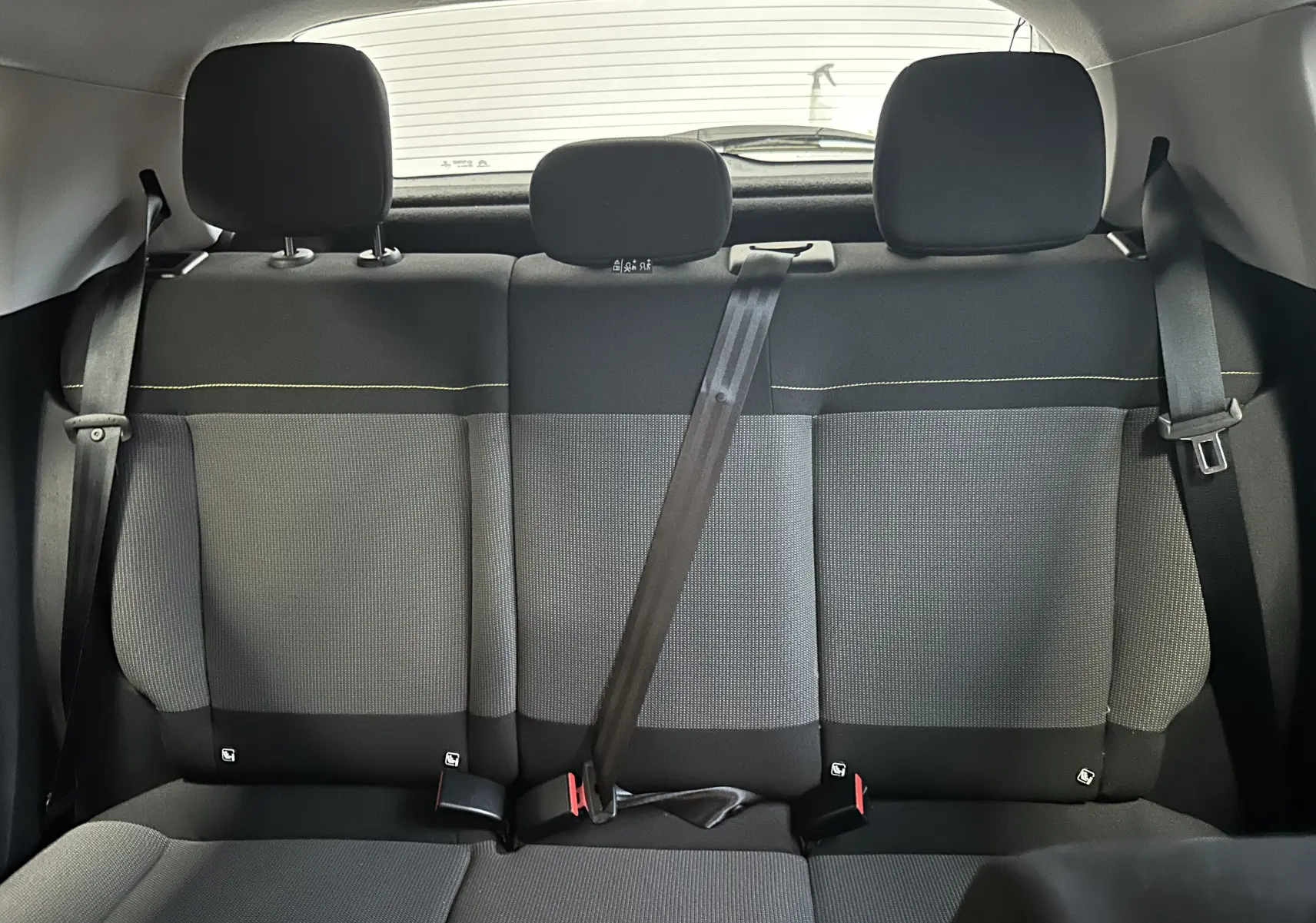 Vue intérieure arrière des sièges arrière gris et noirs de la Citroën C3 III Graphic Ph1, avec ceinture de sécurité centrale attachée.