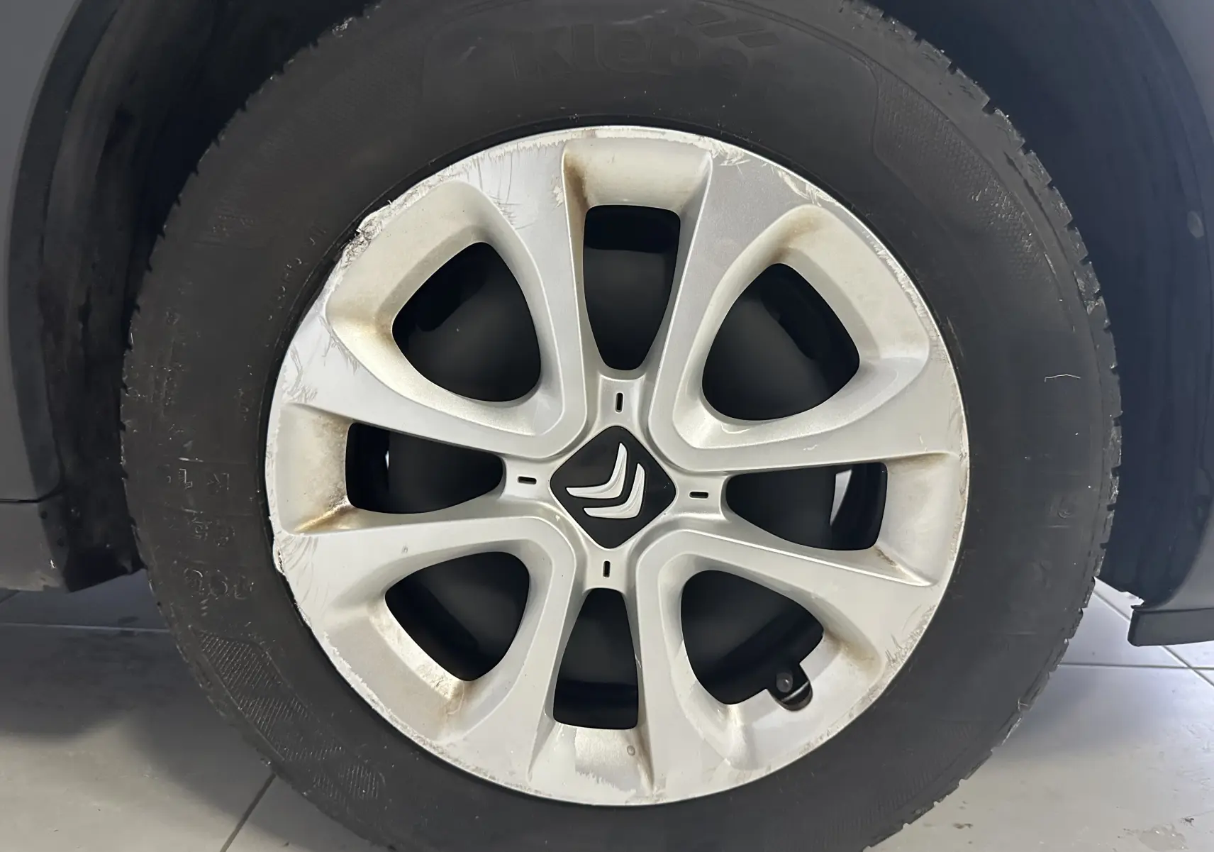 Gros plan sur la roue avant droite d'une Citroën C3 blanche de 2018 avec jante alliage marquée et logo central visible.