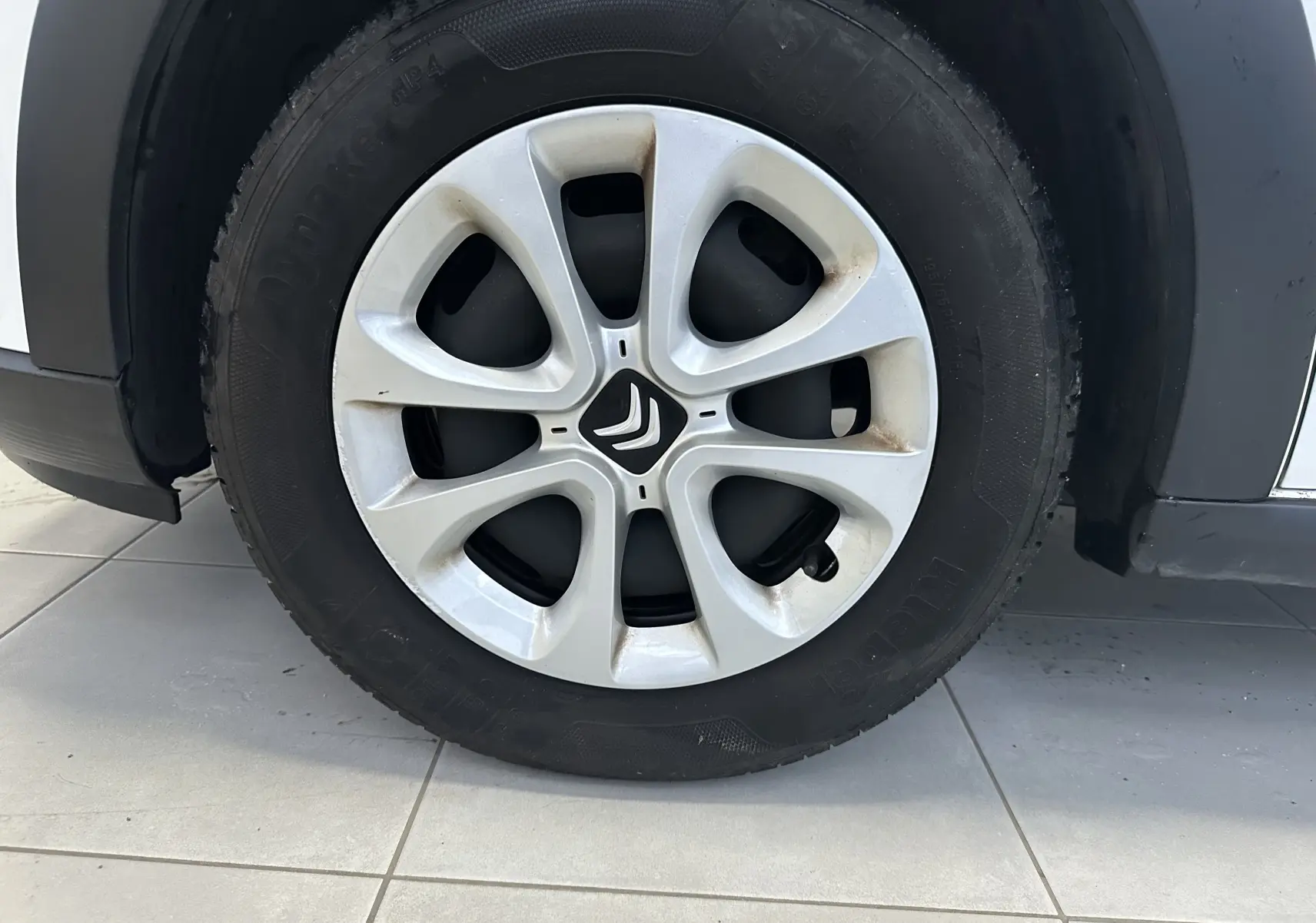 Gros plan sur la roue avant droite d'une Citroën C3 blanche de 2018 avec jante en alliage et logo Citroën central.