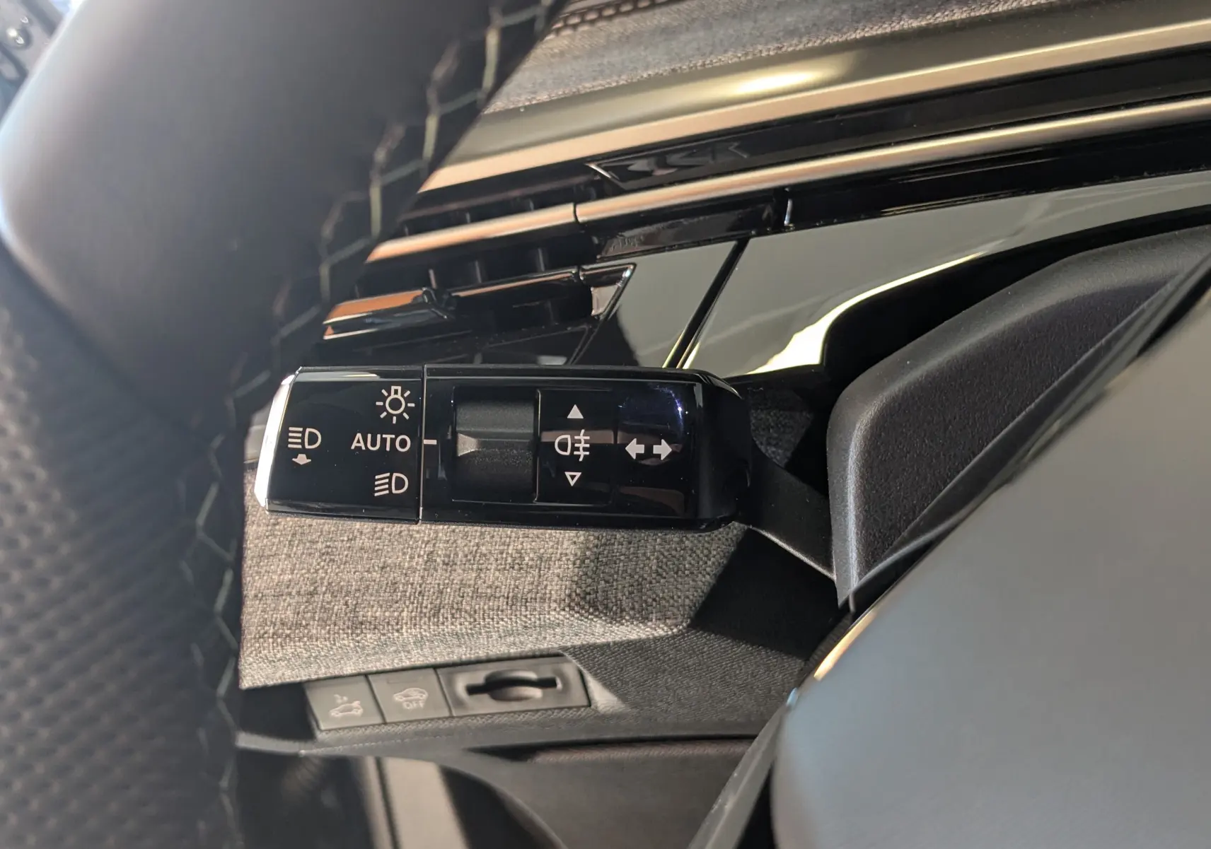 Gros plan sur la commande des feux et clignotants à gauche du volant dans l’habitacle du Peugeot 3008 blanc Okenite 2026.