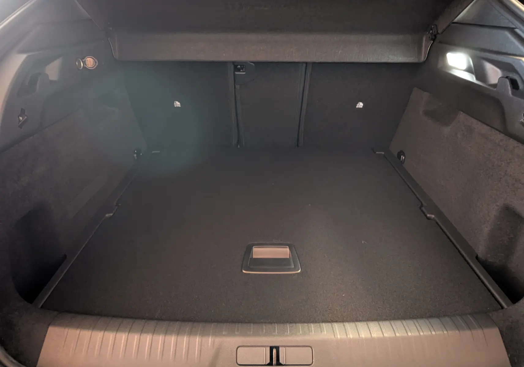 Vue intérieure du coffre spacieux et propre du Peugeot 3008 blanc, avec plancher plat et poignée centrale visible.