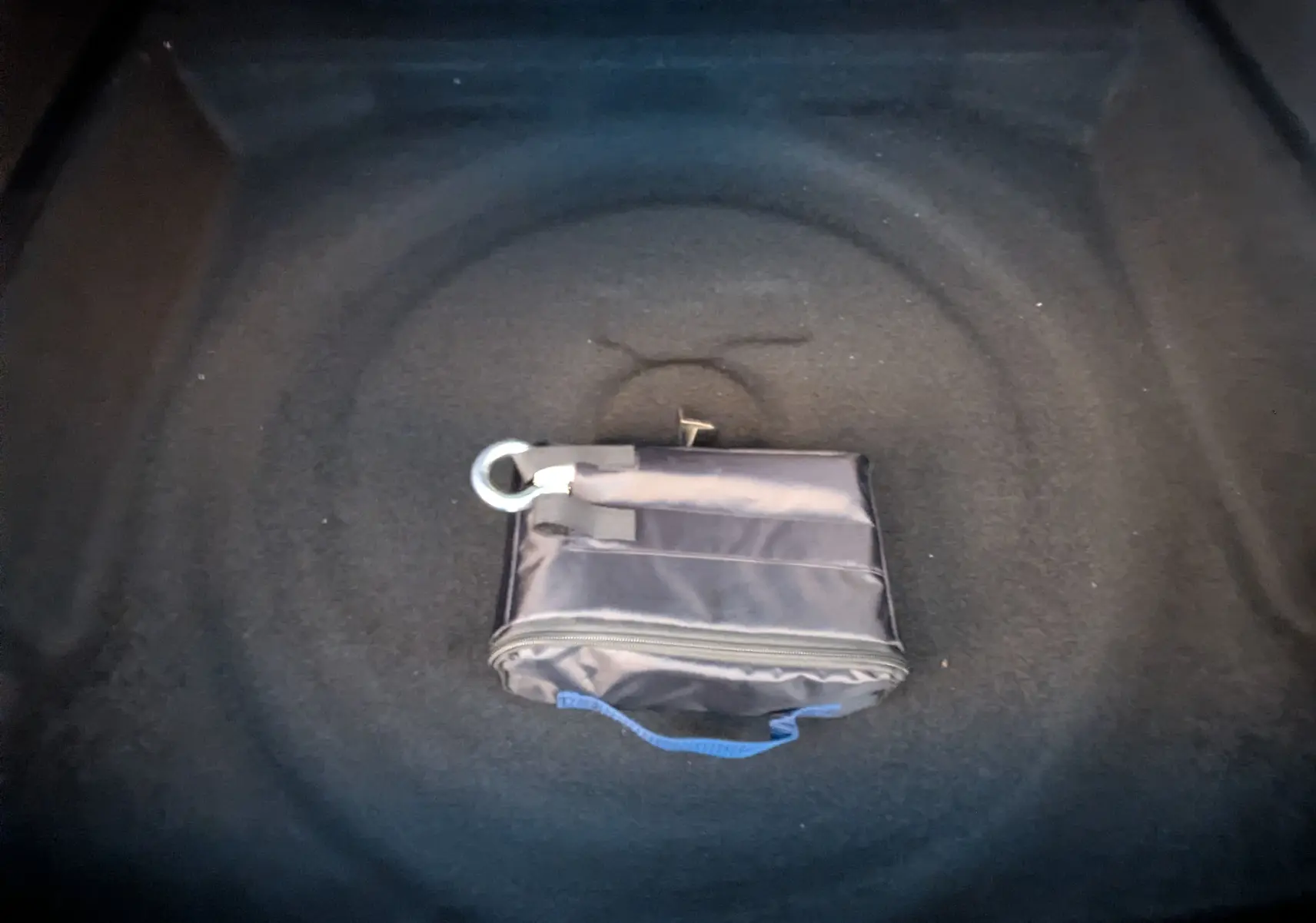 Vue intérieure du coffre d’un Peugeot 3008 blanc Okenite 2026, avec une trousse de réparation pneumatique noire posée au centre.