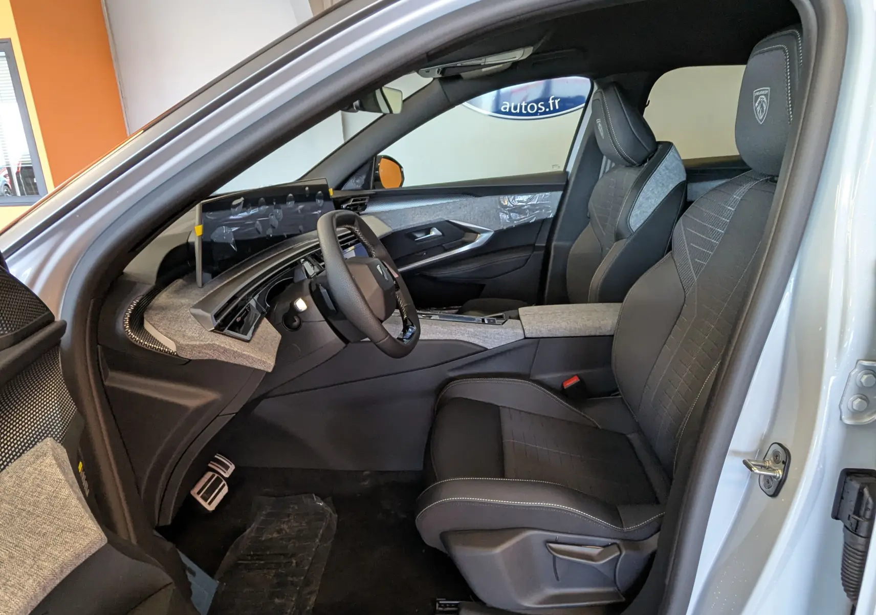 Vue intérieure côté conducteur du Peugeot 3008 blanc Okenite 2026, avec sièges sport et tableau de bord moderne.