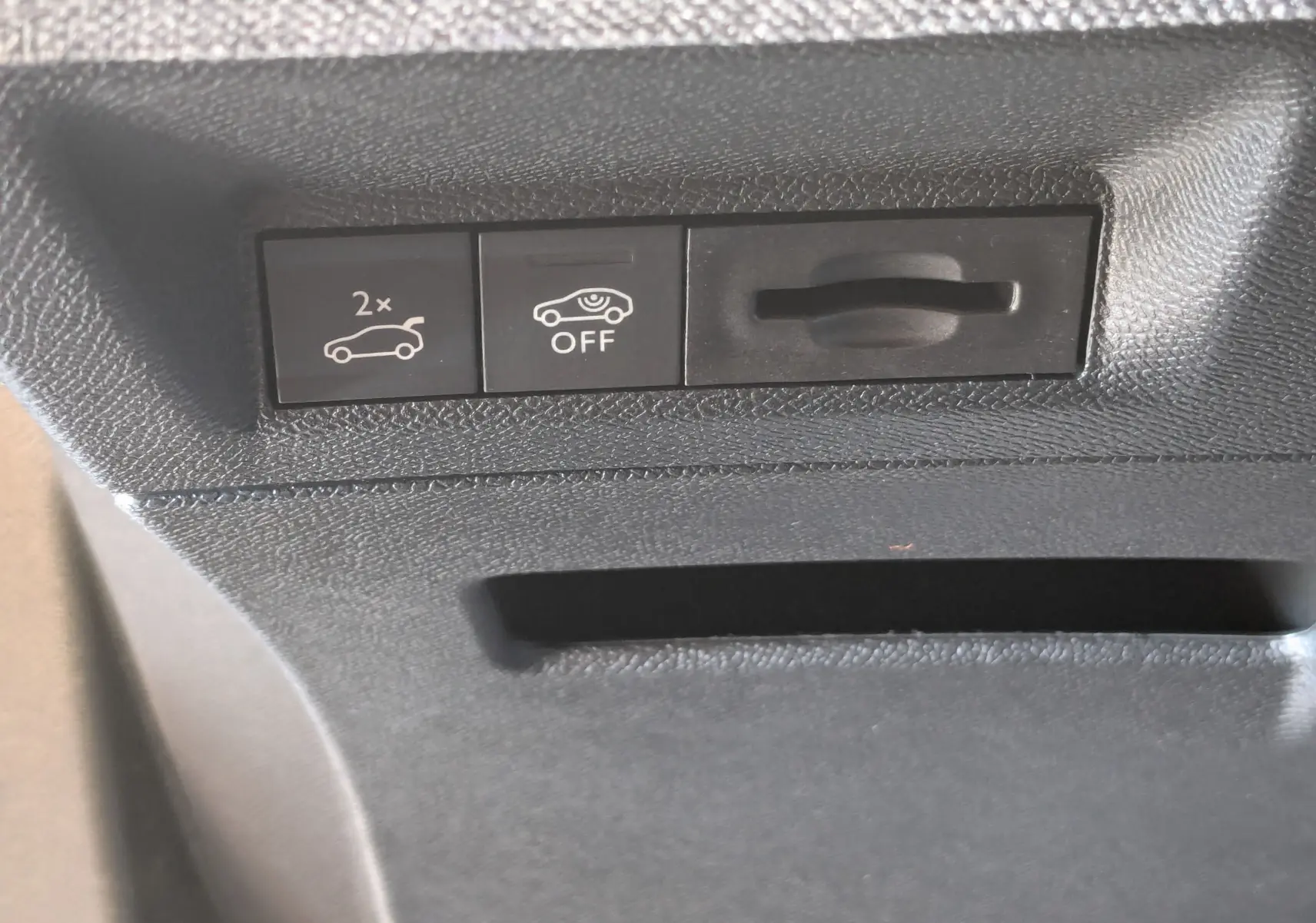 Gros plan sur les commandes intérieures noires du coffre et de l'assistance au stationnement du Peugeot 3008 blanc Okenite.