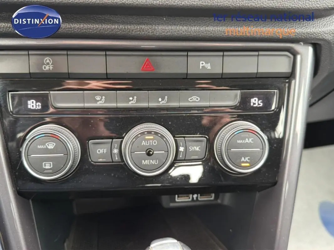Vue rapprochée du tableau de bord du Volkswagen T-Roc noir, mettant en valeur la climatisation automatique et les commandes centrales.