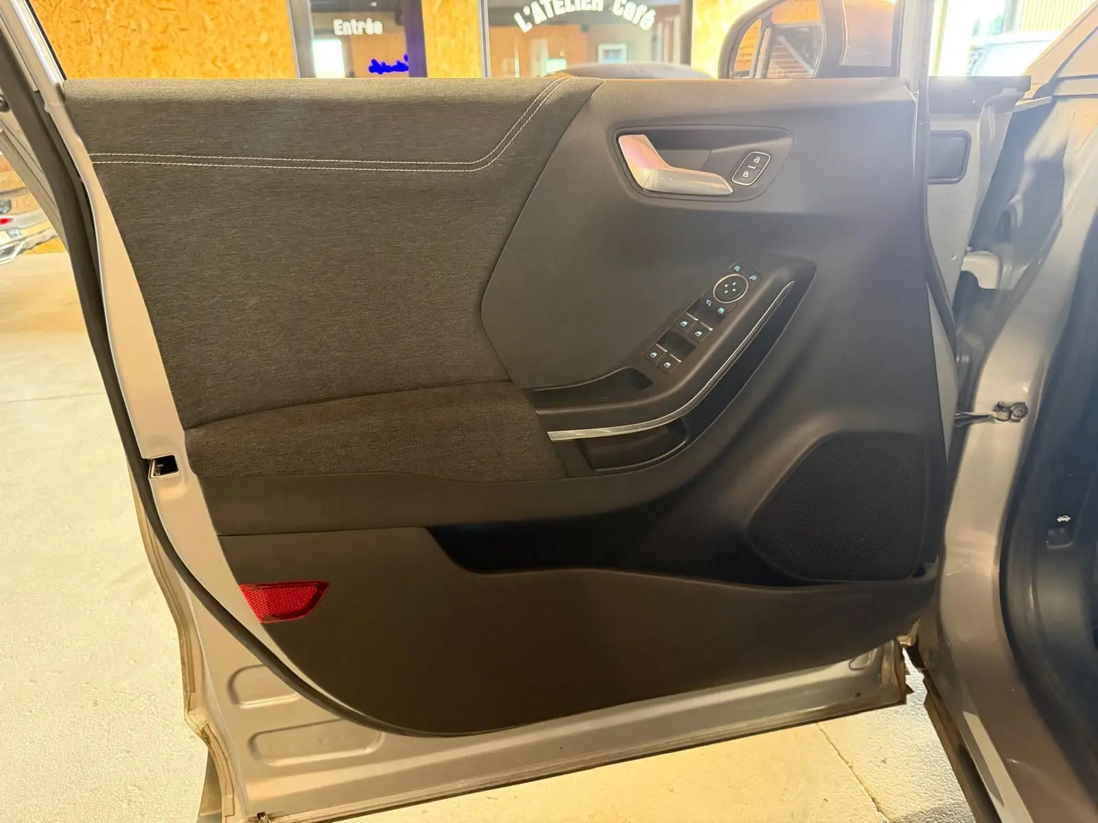 Vue intérieure de la porte avant gauche grise du Ford Puma 1.0 EcoBoost 125 MHEV Titanium avec commandes électriques.