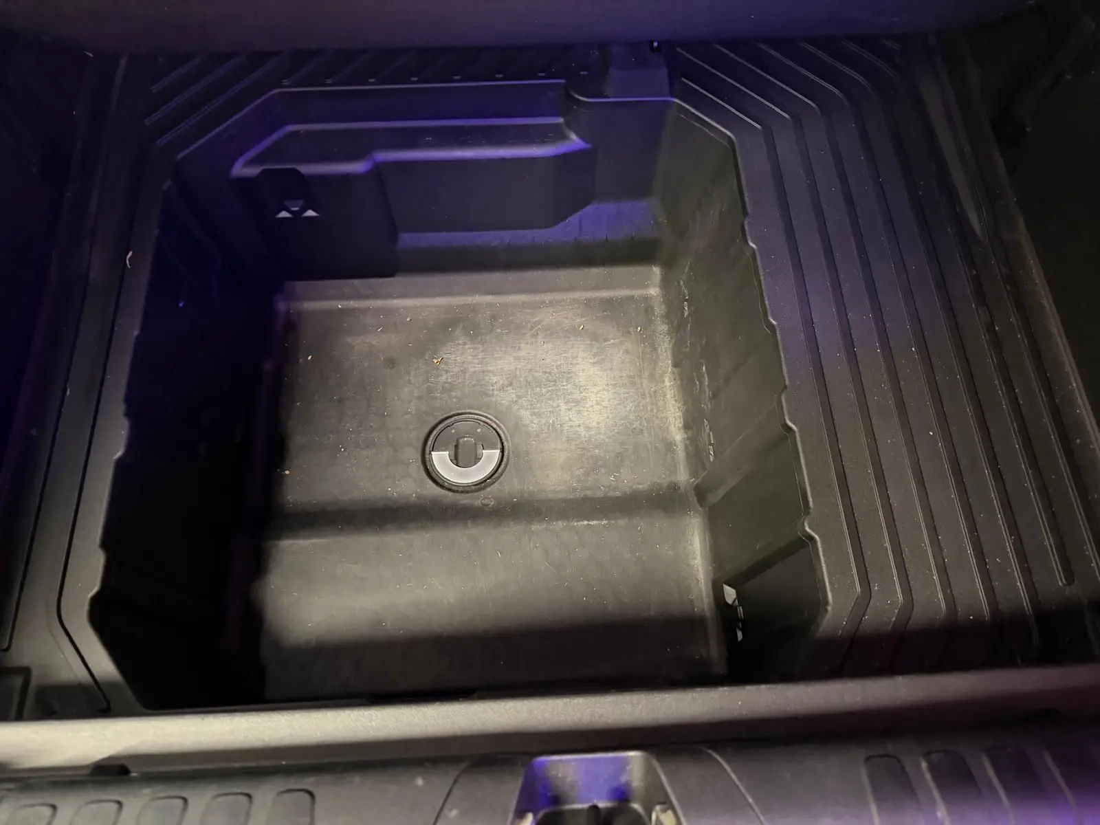 Vue plongeante sur le coffre de rangement sous plancher du Ford Puma gris 2021, espace vide et compartimenté.