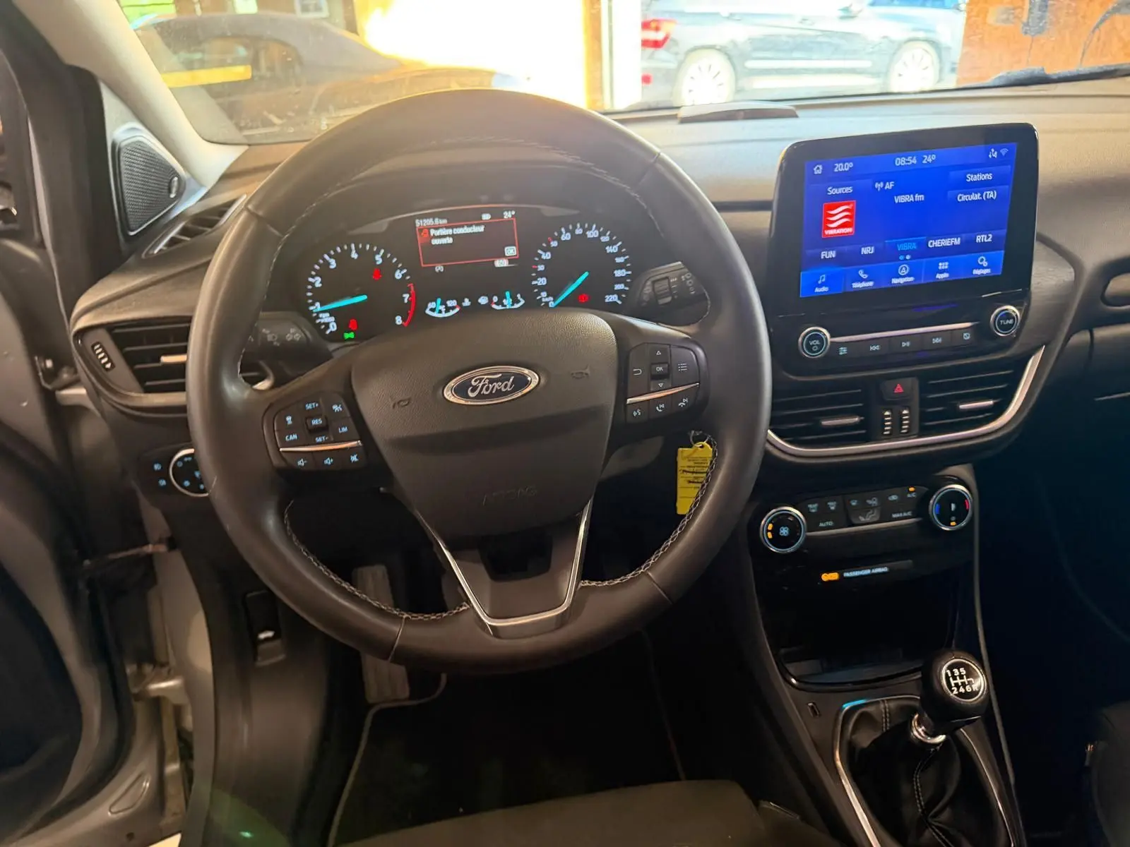 Vue intérieure du tableau de bord et volant noir d'une Ford Puma 1.0 EcoBoost 125 MHEV Titanium avec écran tactile et boîte manuelle.