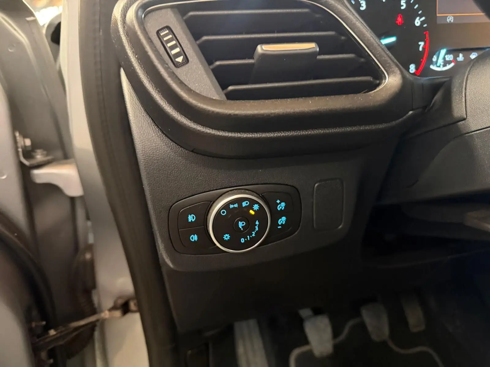 Vue intérieure côté gauche du tableau de bord du Ford Puma gris 2021, avec commandes d'éclairage et pédales visibles.