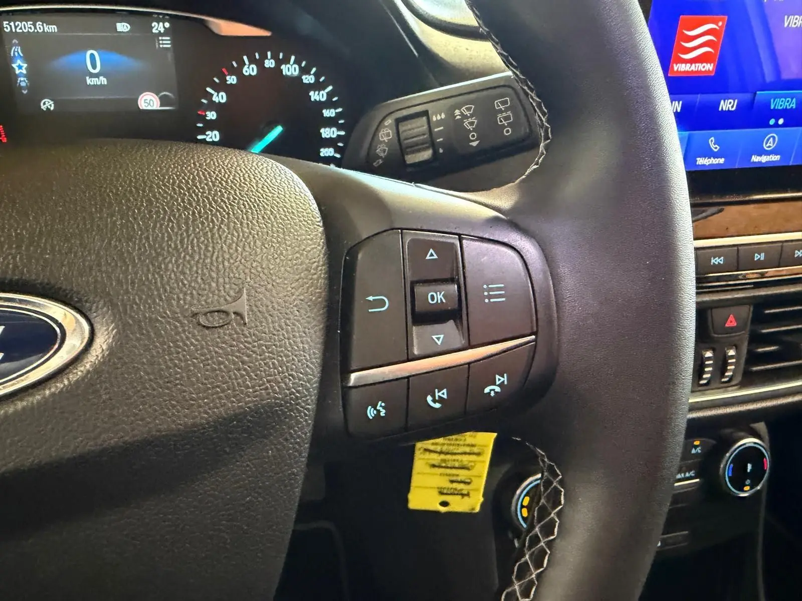 Vue intérieure centrée sur le volant noir de la Ford Puma 2021, avec commandes multifonctions et tableau de bord digital.