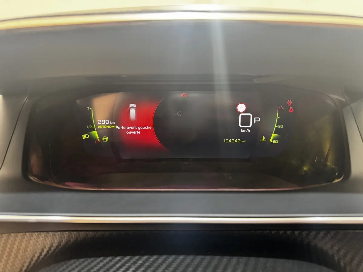 Tableau de bord numérique du Peugeot 2008 noir, affichant porte avant gauche ouverte et compteur kilométrique.