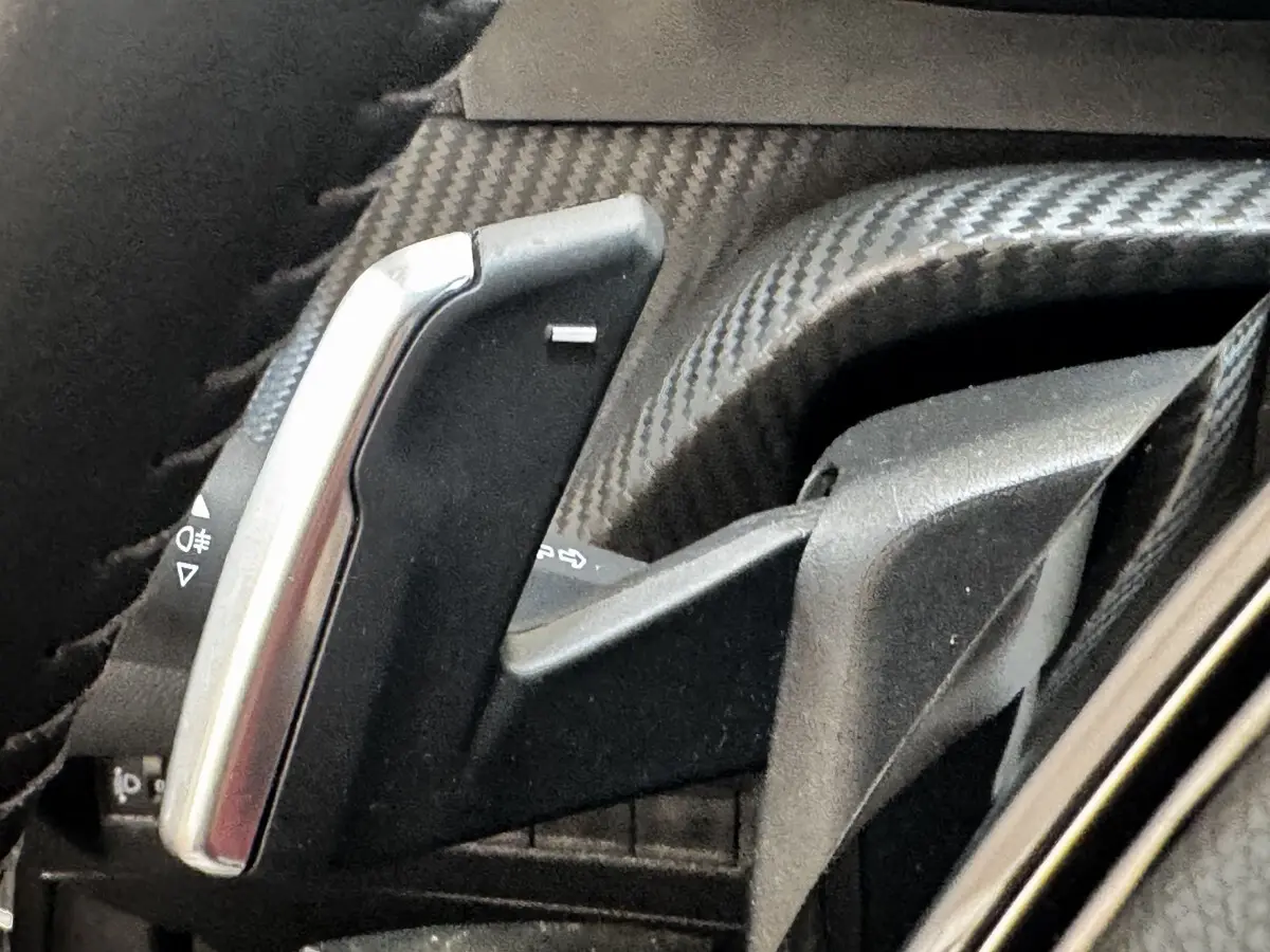 Gros plan sur la palette de changement de vitesse en carbone et métal à gauche du volant du Peugeot 2008 noir.