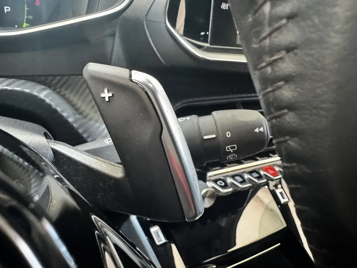 Gros plan sur la palette de changement de vitesse droite en plastique noir et chrome dans l’habitacle noir du Peugeot 2008.