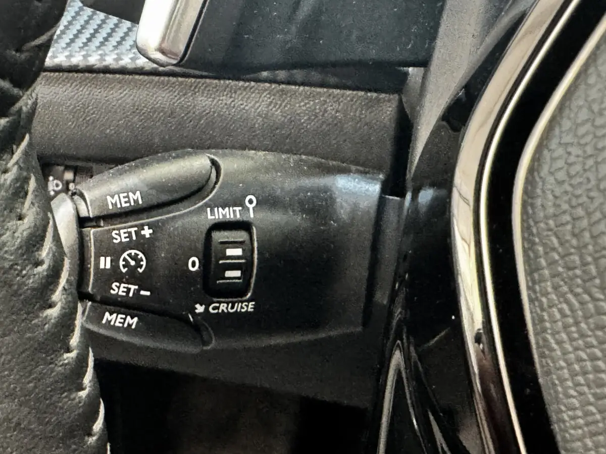 Gros plan sur la commande de régulateur de vitesse au volant cuir noir du Peugeot 2008 BlueHDi 130 2022.
