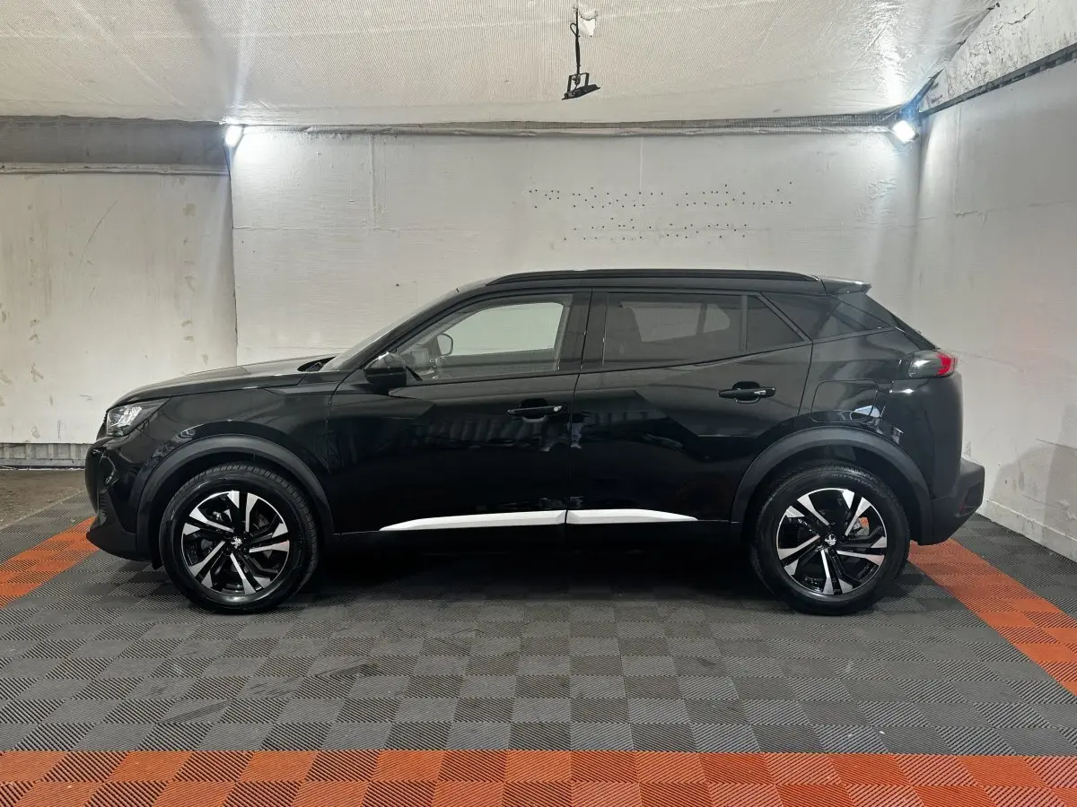 Peugeot 2008 noir vue de profil côté gauche dans un garage, avec jantes alliage bicolores et toit noir.