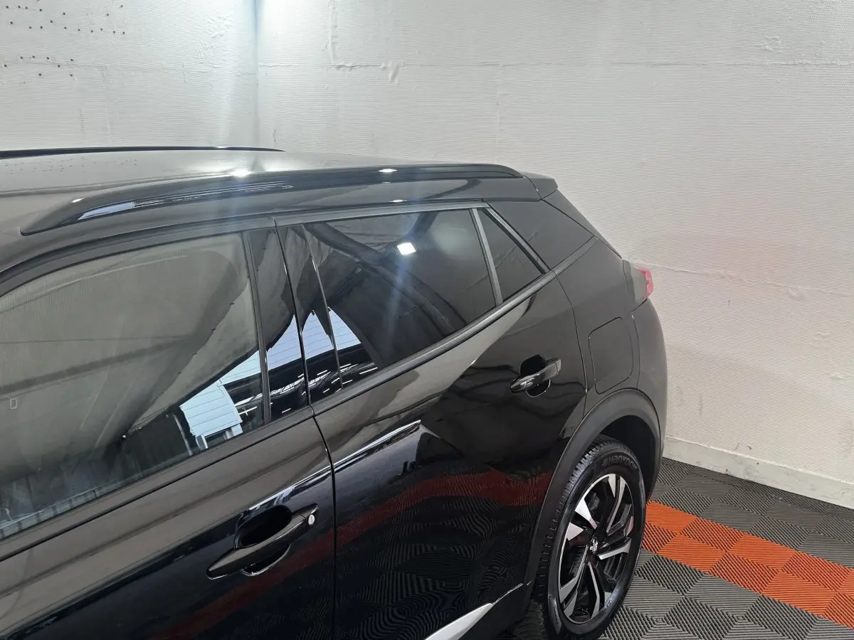 Vue côté droit arrière du Peugeot 2008 noir avec jantes alliage et barres de toit assorties.