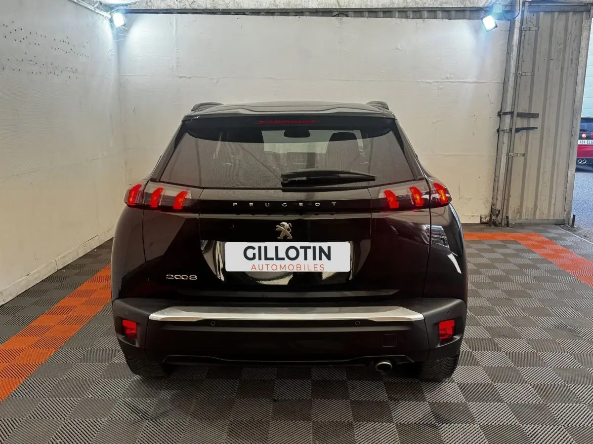 Vue arrière d’un Peugeot 2008 noir 2022 avec feux arrière LED et logo Peugeot visible sur un sol à damiers gris et orange.